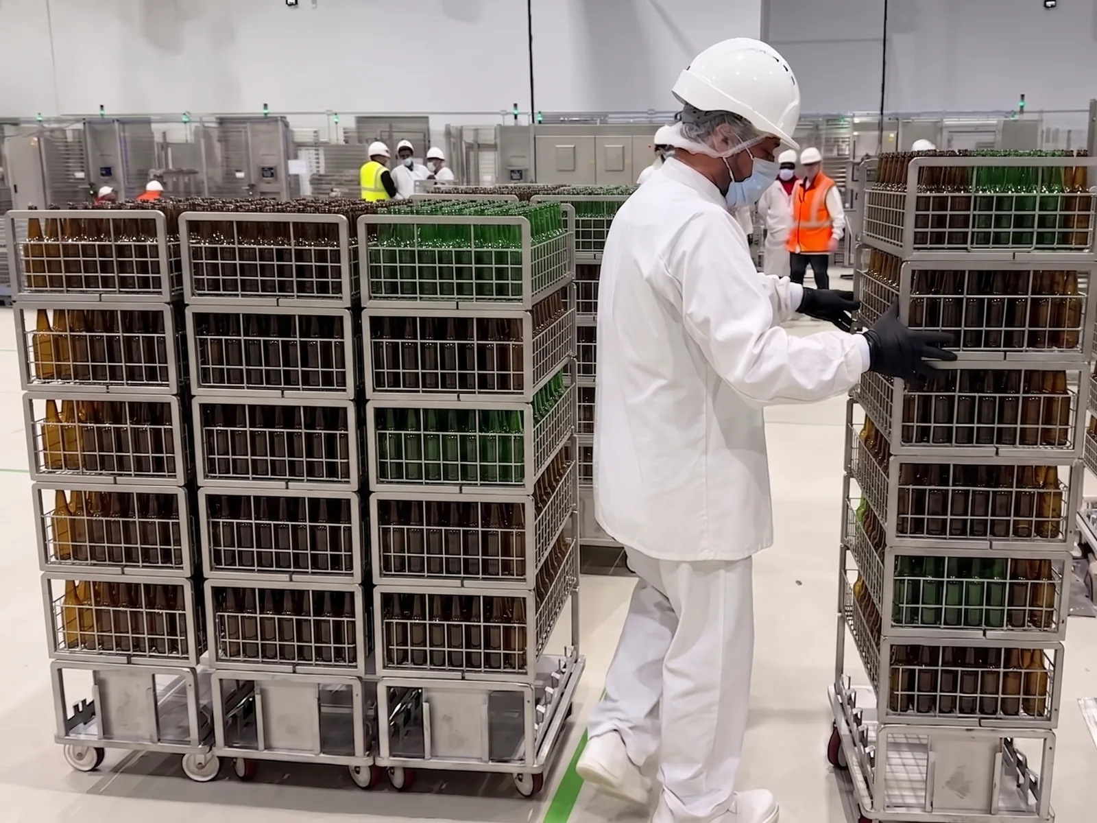 Rolls chargés de bouteilles consignées manœuvrés par un opérateur dans une laverie industrielle