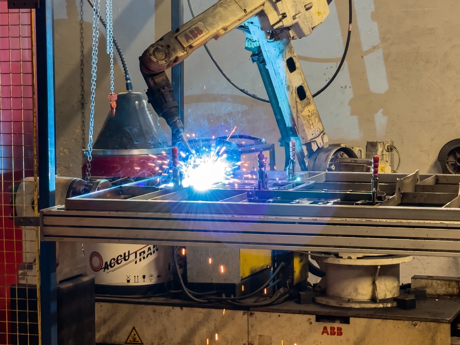 Bras robotisé en pleine soudure sur un châssis métallique, en atelier de fabrication